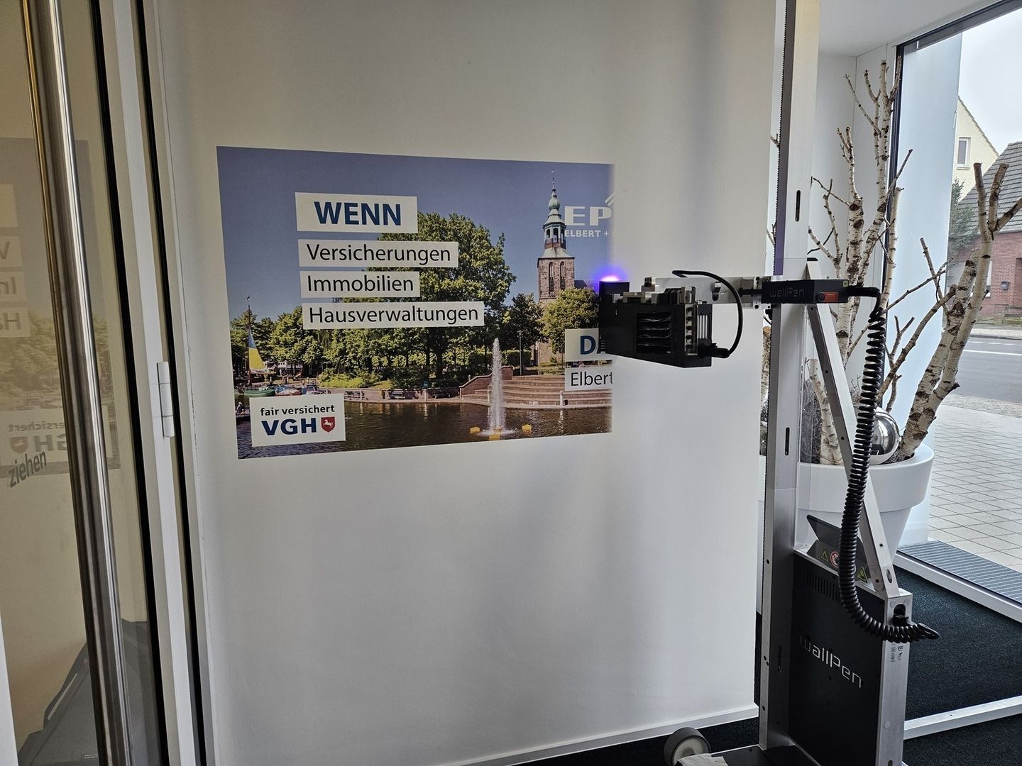 Mobiler Wanddrucker projiziert Versicherungsplakat mit Text Wenn Versicherungen Immobilien Hausverwaltungen in einem Büro- oder Ausstellungsraum